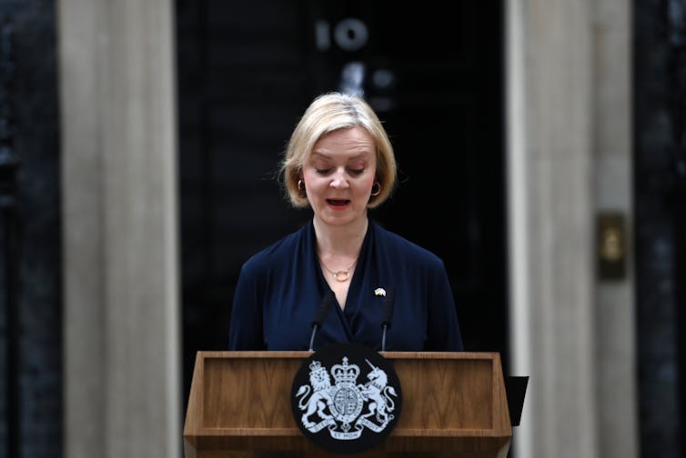 Liz Truss speaking at a podium in front of Number 10 Downing Street to announce her resignation