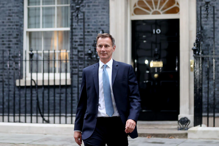 A man in a blue suit and tie outside a black door.
