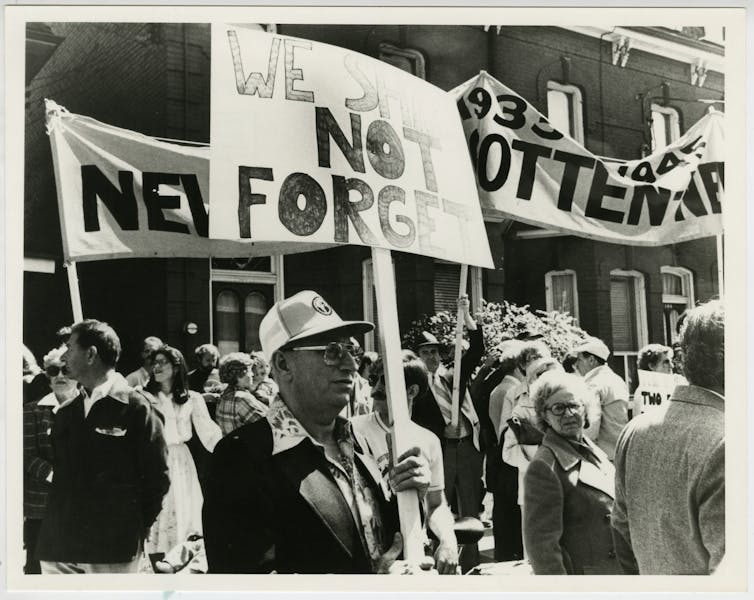 A man seen holidng a sign that says 'We shall not forget.'