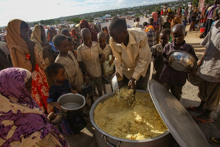 Women with their hair covered queueing for food.