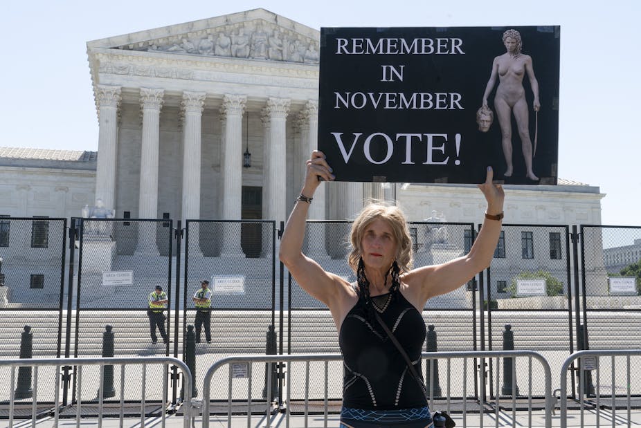 A woman holds a sign with an image depicting Medusa that says, "Remember in November, Vote!," outside of the Supreme Court in Washington.