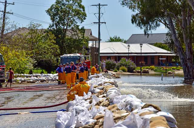 emergency services behind a wall of sandbags protecting houses