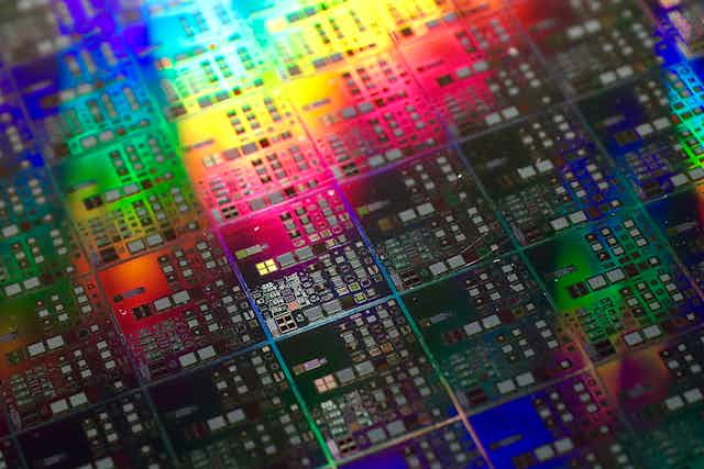 A close up photo of a silicon chip with rainbow reflections.