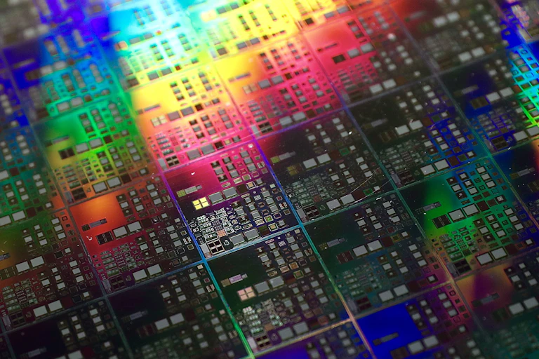 A close up photo of a silicon chip with rainbow reflections.
