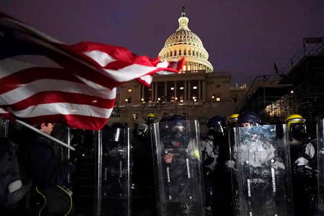 Riot police and US flag flying in front of US Capitol at night