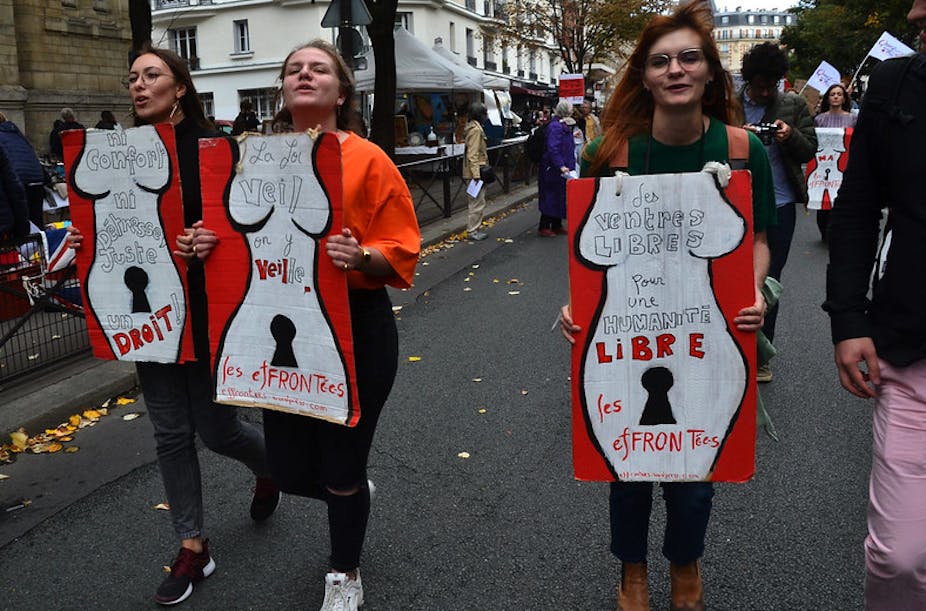 Trois femmes portent des panneaux représentant des corps de femmes inscrits de mentions pour le droit à disposer de leurs coprs