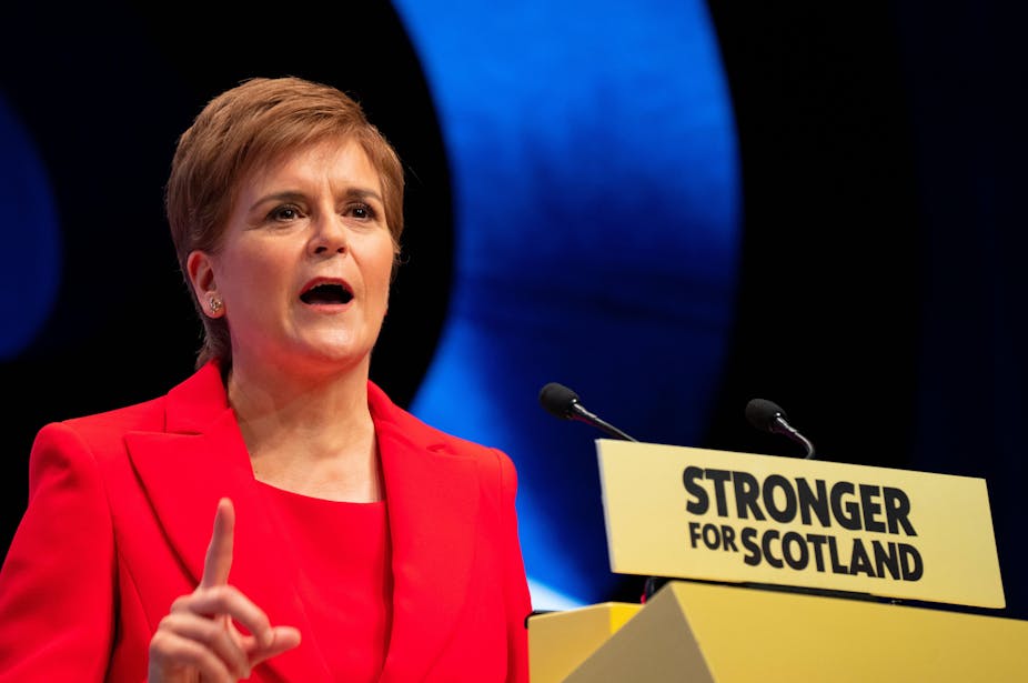 Nicola Sturgeon speaking at a podium that reads Stronger for Scotland