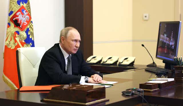 Vladimir Putin sits at his desk talking via video link with members of the Security Council, October 2022.