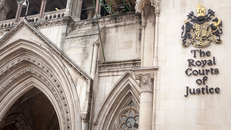Close up of the front door of the Old Bailey, with the Royal Courts of Justice sign and insignia on the concrete