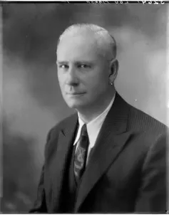 A man wearing a suit poses for a black and white photo.