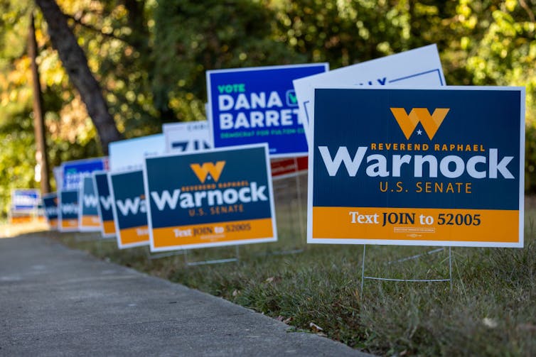 A lawn lined with signs of U.S. Senate candidate Raphael Warnock.