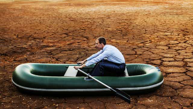 Man on inflatable rowing boat on dried ground