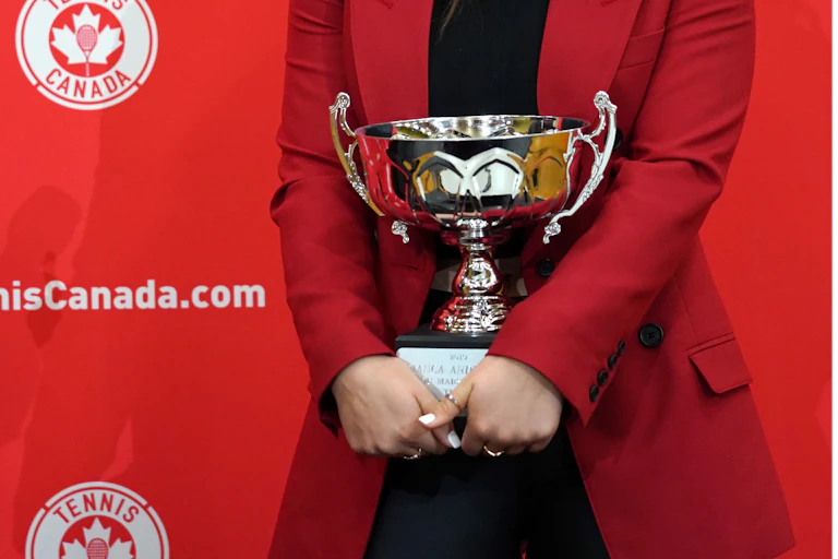A silver trophy being held by a woman wearing a red jacket.
