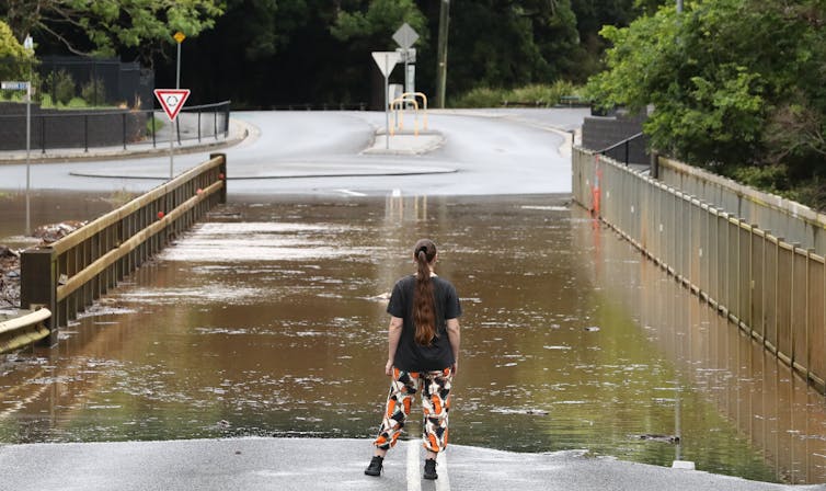woman stands and looks at flood waters