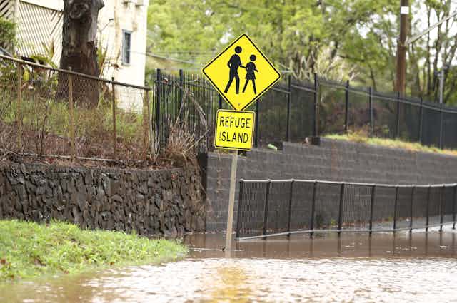 street sign with two figures reads 'refuge island' footpath is flooded