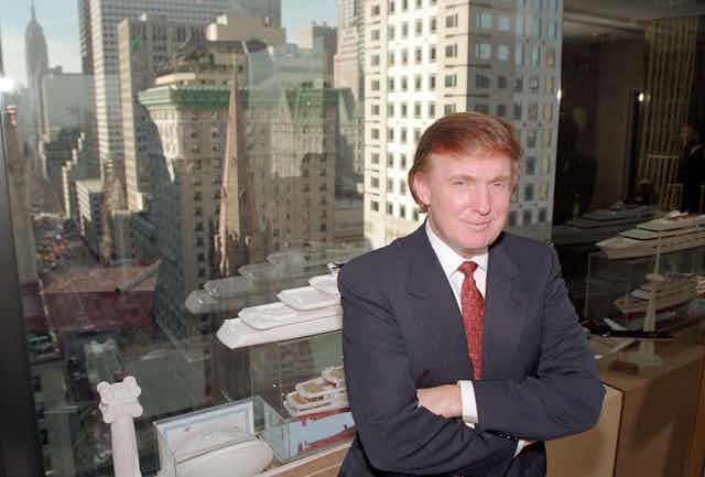 Donald Trump stands in front of New York skyscrapers.