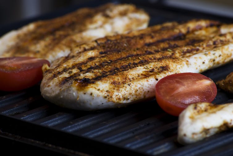 Chicken is grilled on a barbecue.