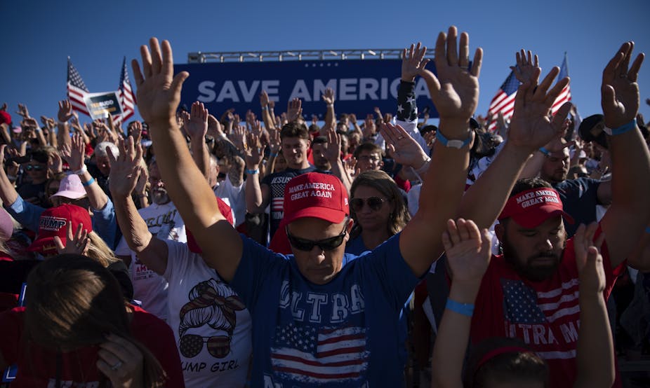 People in Trump t-shirts and caps praying during an election rally