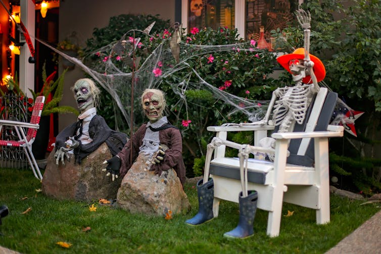 skeleton and two zombies decorate front yard