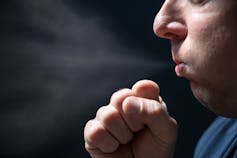 Man coughing into clenched fist.
