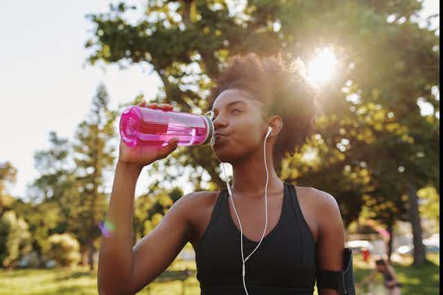 A young woman drinks from a water bottle.