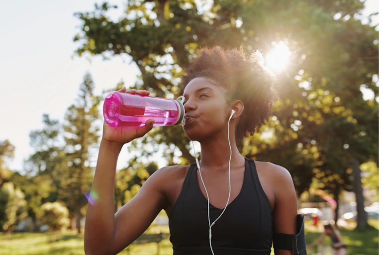 A young woman drinks from a water bottle.