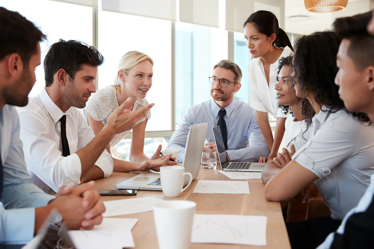A group of people dressed formally sit around a table talking.