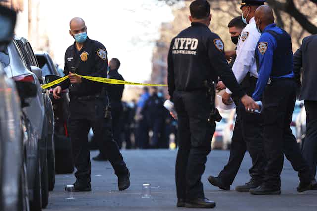 Police officers walk past a yellow police ribbon on a New York City street 