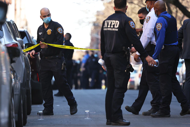 Police officers walk past a yellow police ribbon on a New York City street