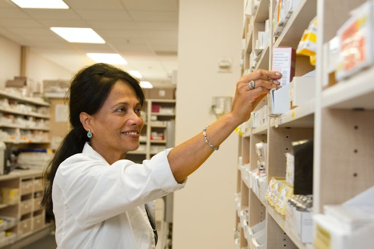 Pharmacist pulls medicine off a shelf