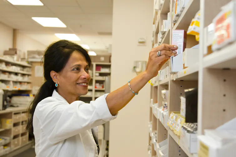 Pharmacist pulls medicine off a shelf