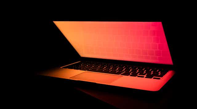 Laptop bathed in orange and red light