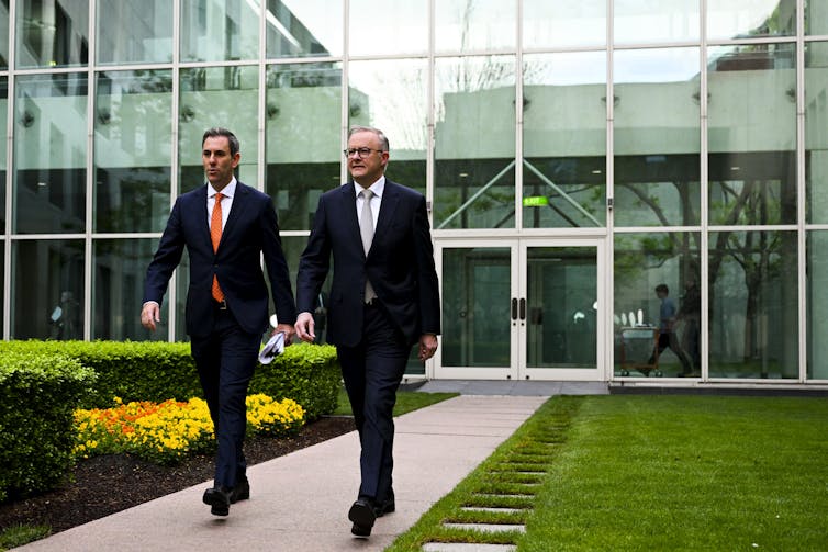 two men in suits walk down path