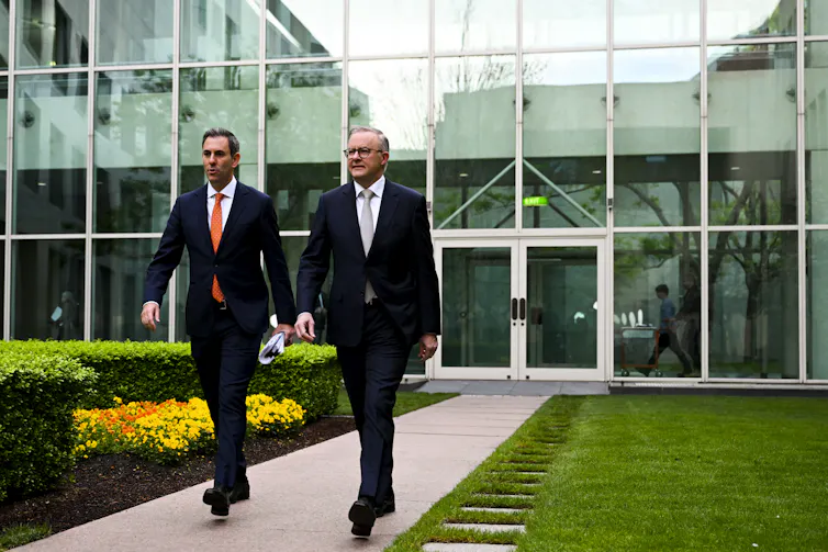 two men in suits walk down path