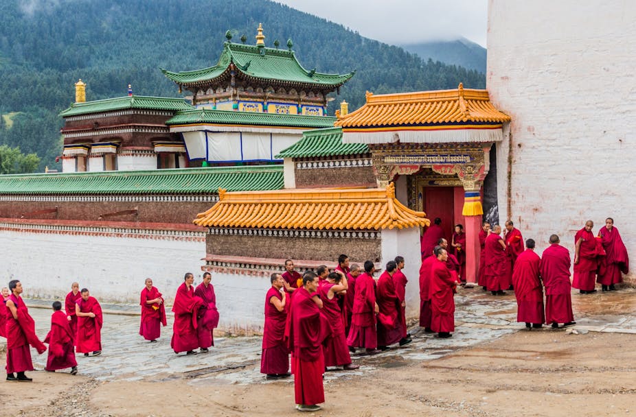 Monks in red garments gather outside a monastry in China. 