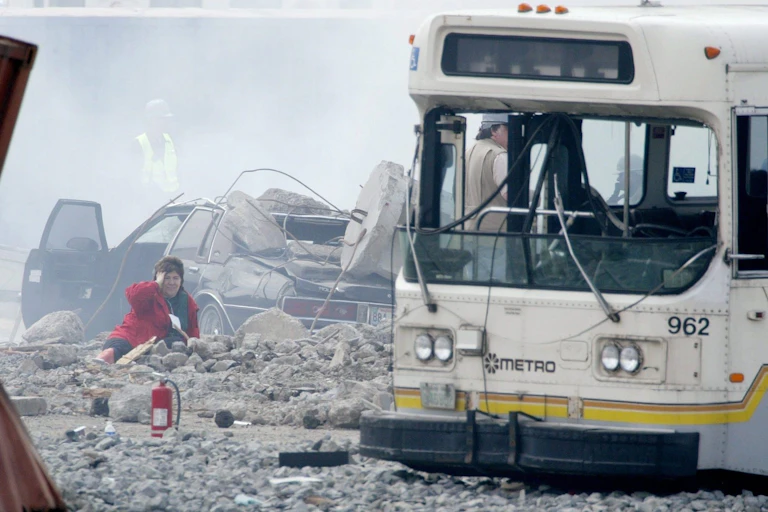 A woman holds her head as she lies in the rubble caused by the explosionof a fake 'dirty bomb'. A wrecked bus sits nearby.