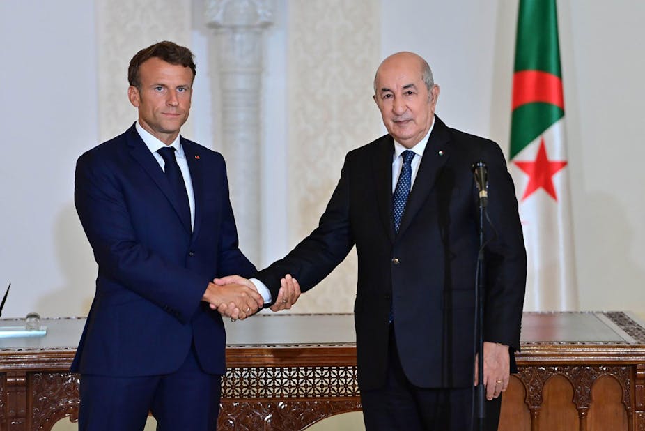 Emmanuel Macron shakes hands with Algerian president Abdelmadjid Tebboune