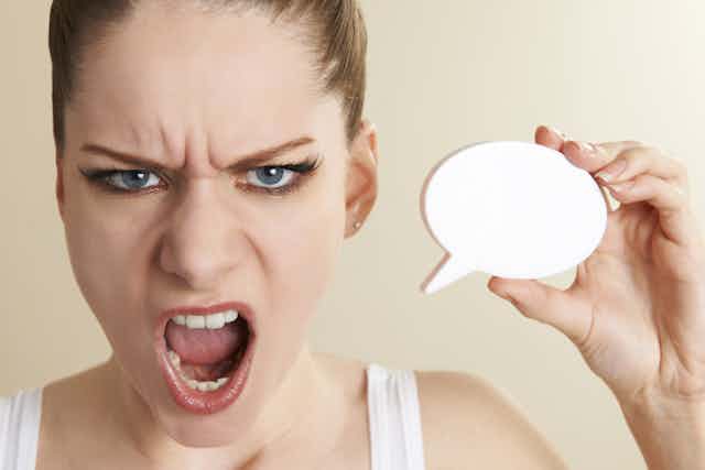Close up of angry woman holding a black speech bubble