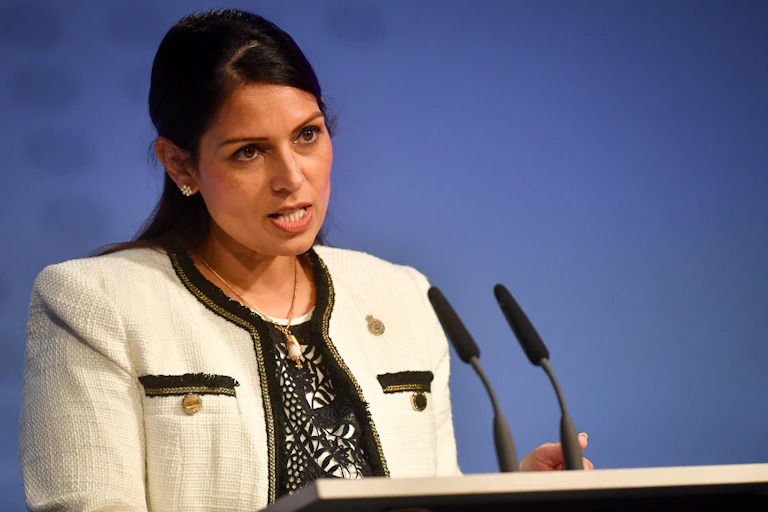 A woman in a white dress suit speaks at a lecturn.