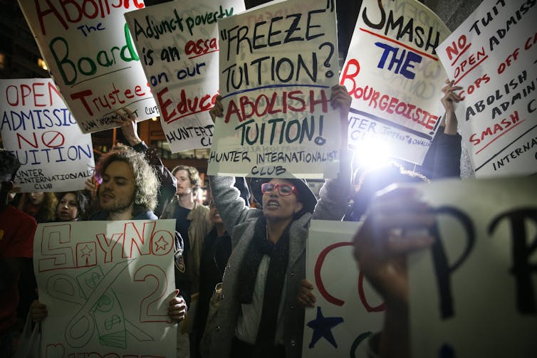 Students holding placards saying 'Freeze tuition, abolish tuition,' among others.