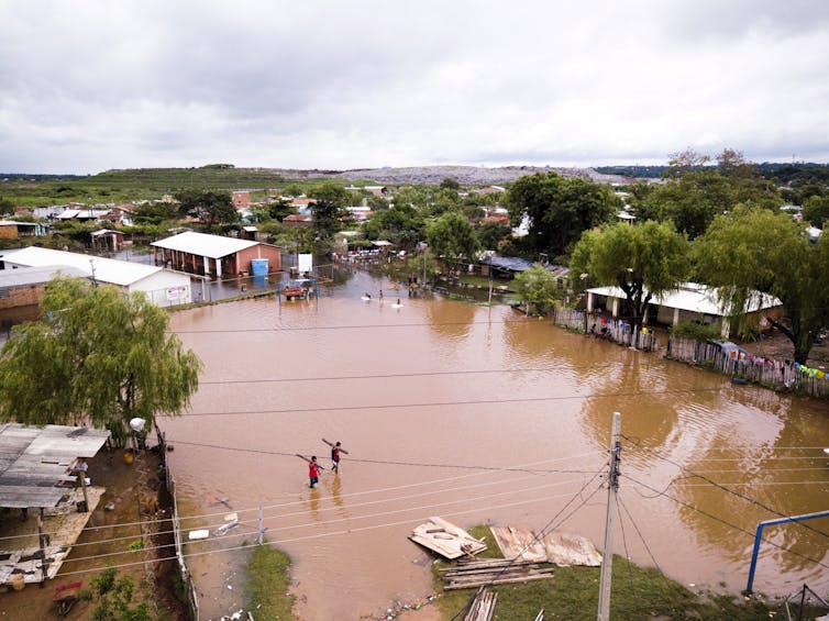 Men carrying boards wade on a flooded soccer field