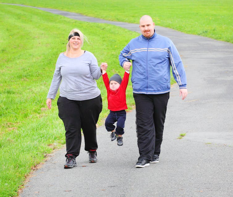 Overweight parents walking outdoors with their child