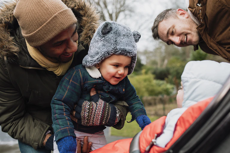 Two dads play with their kids in a park.