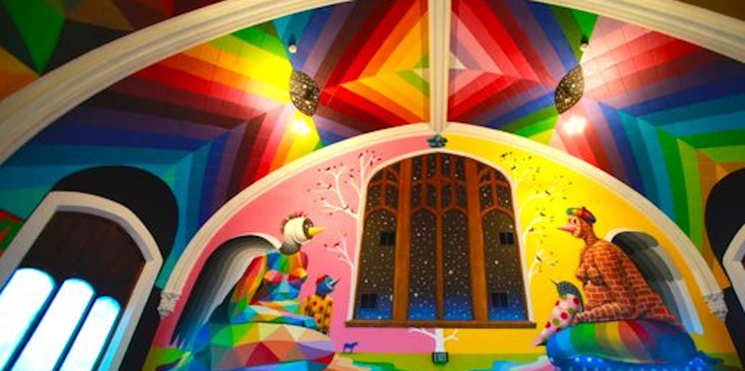 A church with a flamboyant technicolor interior, with a mural on the  wall showing two figures smoking weed.