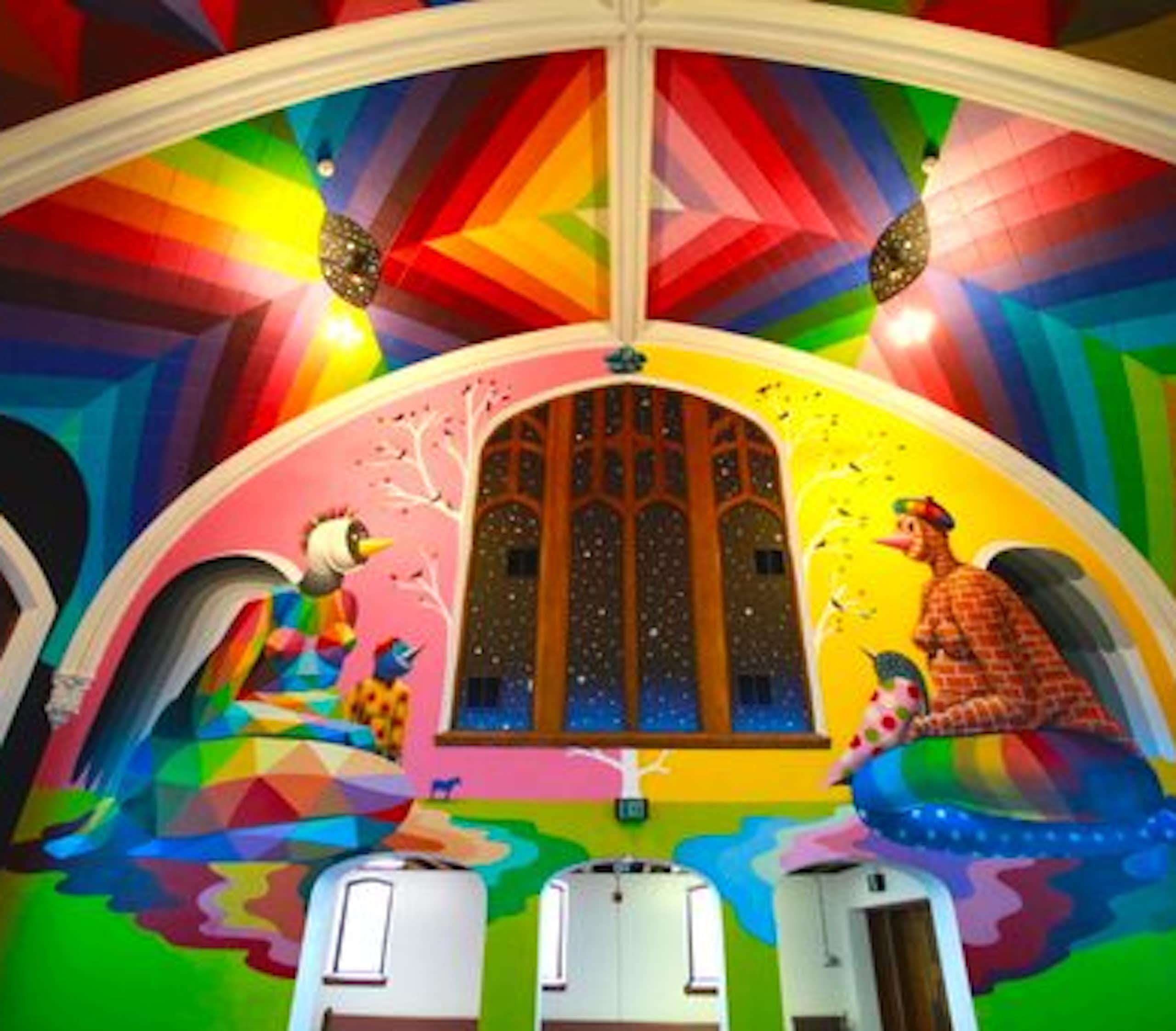 A church with a flamboyant technicolor interior, with a mural on the  wall showing two figures smoking weed.
