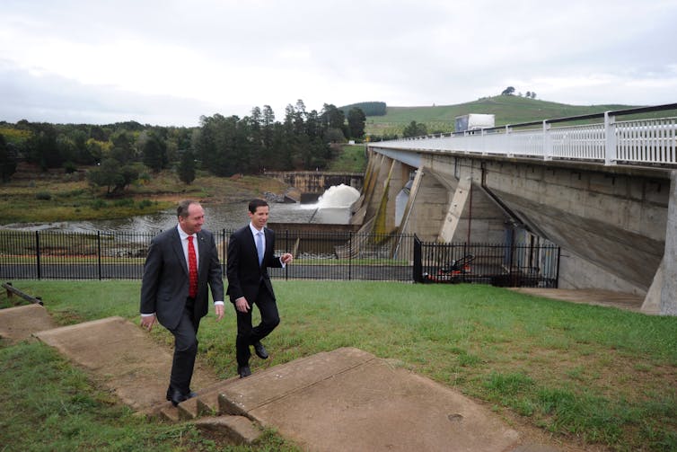 Two men walking near a dam