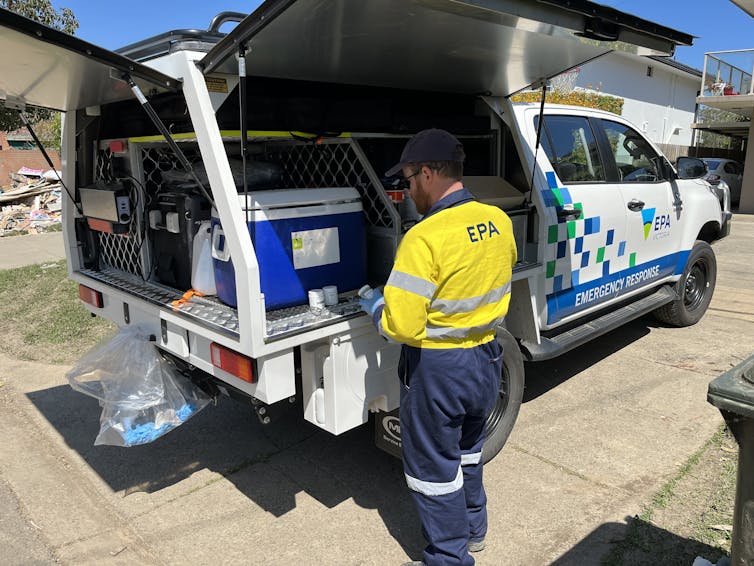 EPA worker stands next to his vehicle as he labels newly collected samples