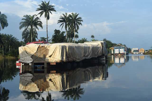 Picture shows trucks with goods abandoned on East-West highway cut off by flood at Ahoada district of Rivers State on October 22, 2022. - Flooding is frequent during Nigeria's rainy season but this year, more than 600 people have died and 1.3 million others were forced to leave their homes, according to the latest government figures. (Photo by PIUS UTOMI EKPEI / AFP) (