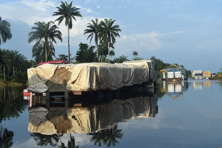 Picture shows trucks with goods abandoned on East-West highway cut off by flood at Ahoada district of Rivers State on October 22, 2022. - Flooding is frequent during Nigeria's rainy season but this year, more than 600 people have died and 1.3 million others were forced to leave their homes, according to the latest government figures. (Photo by PIUS UTOMI EKPEI / AFP) (