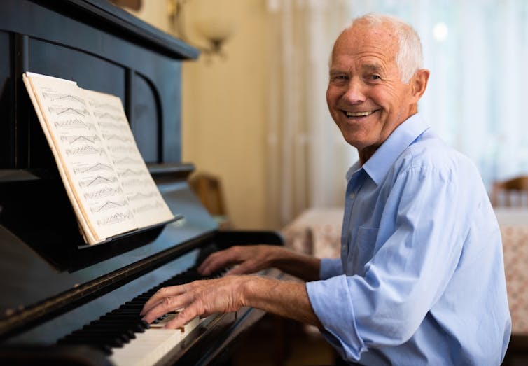 Old man smiling as he plays the piano